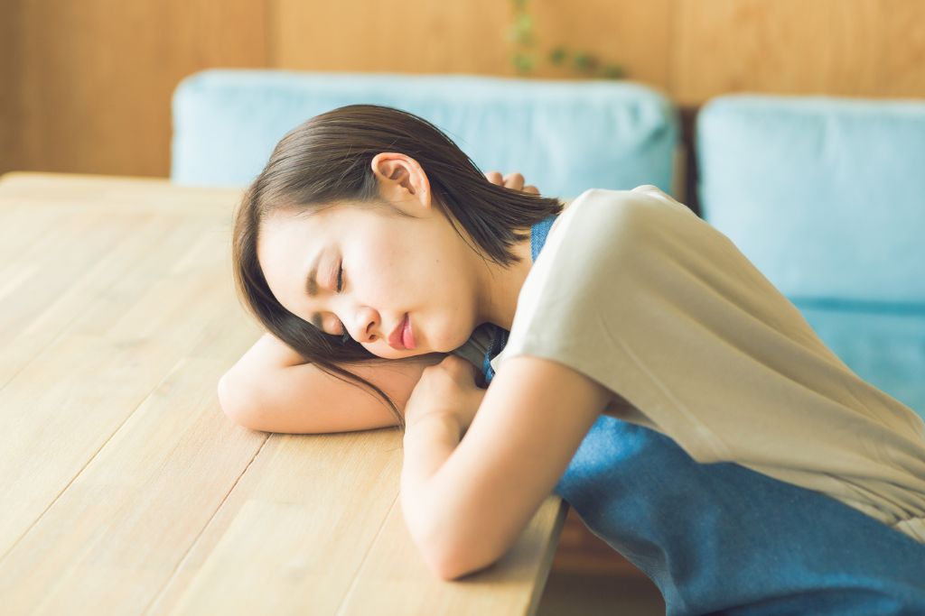 慢性的な疲労でテーブルに突っ伏している女性